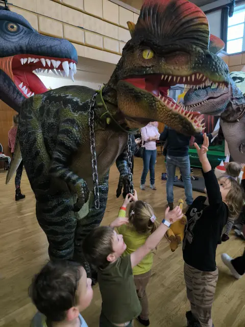 Děti nadšeně sahají na dinosauří kostým