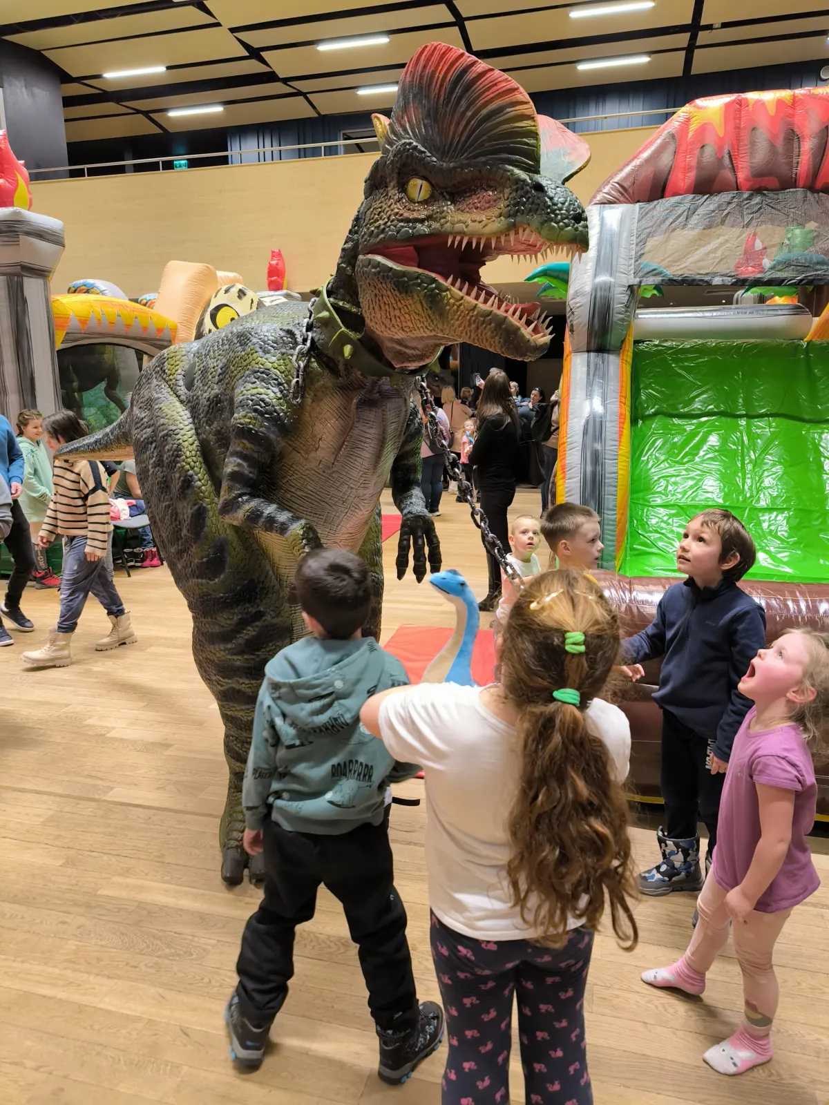 Animátor v kostýmu dinosaura mezi dětmi